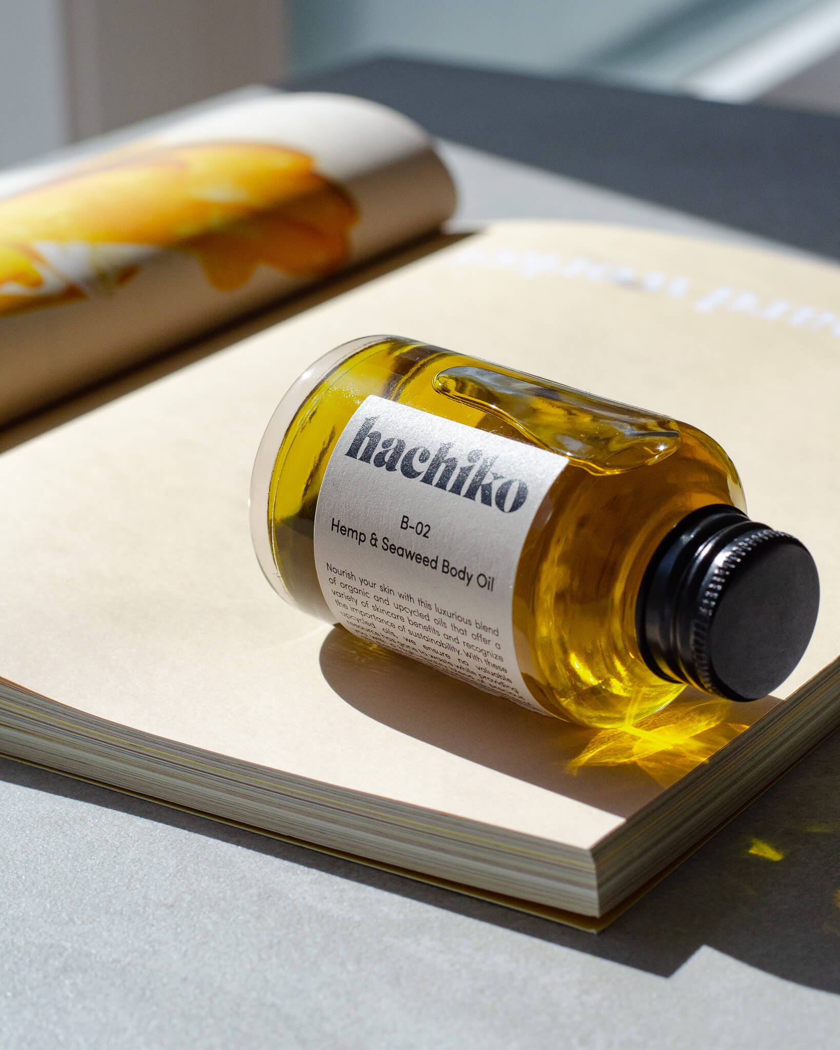 Hemp & Seaweed Body Oil liegt in der Sonne auf einem aufgeschlagenem Magazin